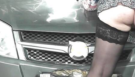 Sexy MILF without panties in boots and stockings is polishing car in garage. No panties under skirt. Naked in public