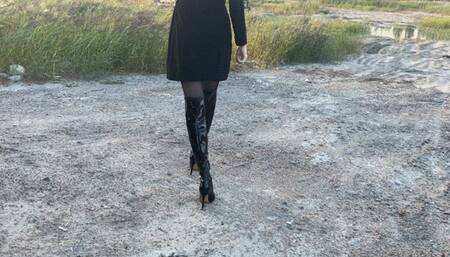 girl in high-heeled leather boots walks through the swamp, her boots get wet