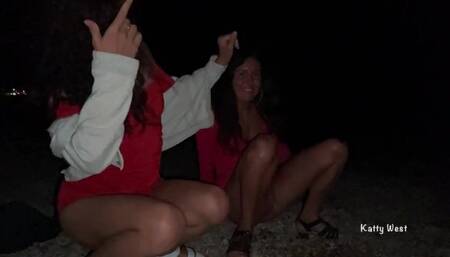 Two girls pissing on a public promenade on the beach