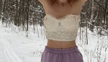 A girl in a terrible frost stands in the forest in ballet flats, shorts and a top and shakes from the cold