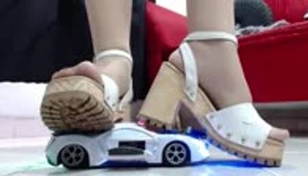 crushing a police toy car robot with nylons and hard soled wooden sandals