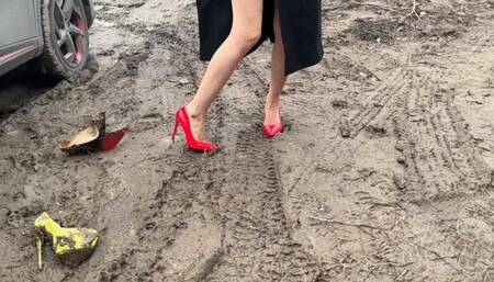 A girl in sexy red shoes walks through sticky mud that sucks her shoes inside herself