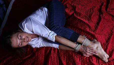 Delta: barefoot girl in white shirt with rolled up sleeves and blue skinny cuffed jeans, balltied with rope, wiggles on the bed (HD MOV)