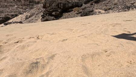 Naked girl lies on the sand and pee