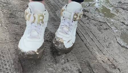 A girl in fashionable snow-white sneakers He walks on slippery, sticky mud and gets his hands dirty and crush her sneakers