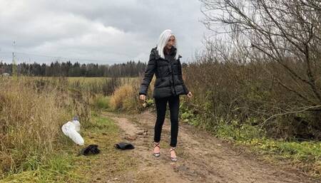 A girl in strappy shoes goes for a walk in rainy weather, there are puddles everywhere and mud that covers her shoes and feet