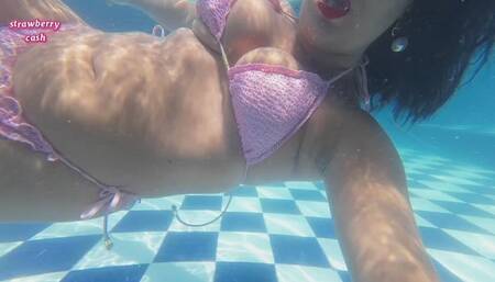Blowing bubbles in the swimming pool in a pink bikini